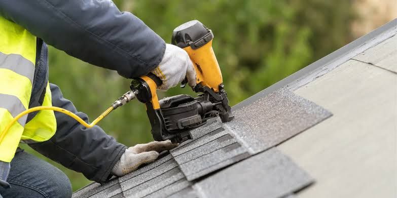 Close view of a nail gun fastening a shingle